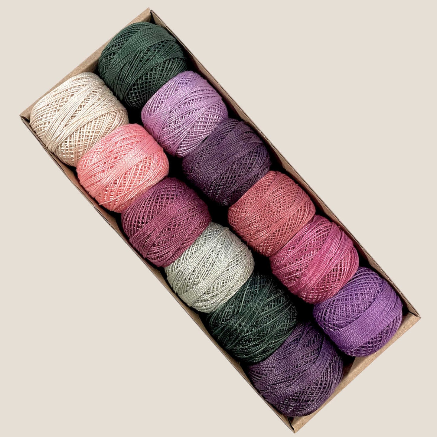 Box of colorful perle cotton thread balls on a beige background