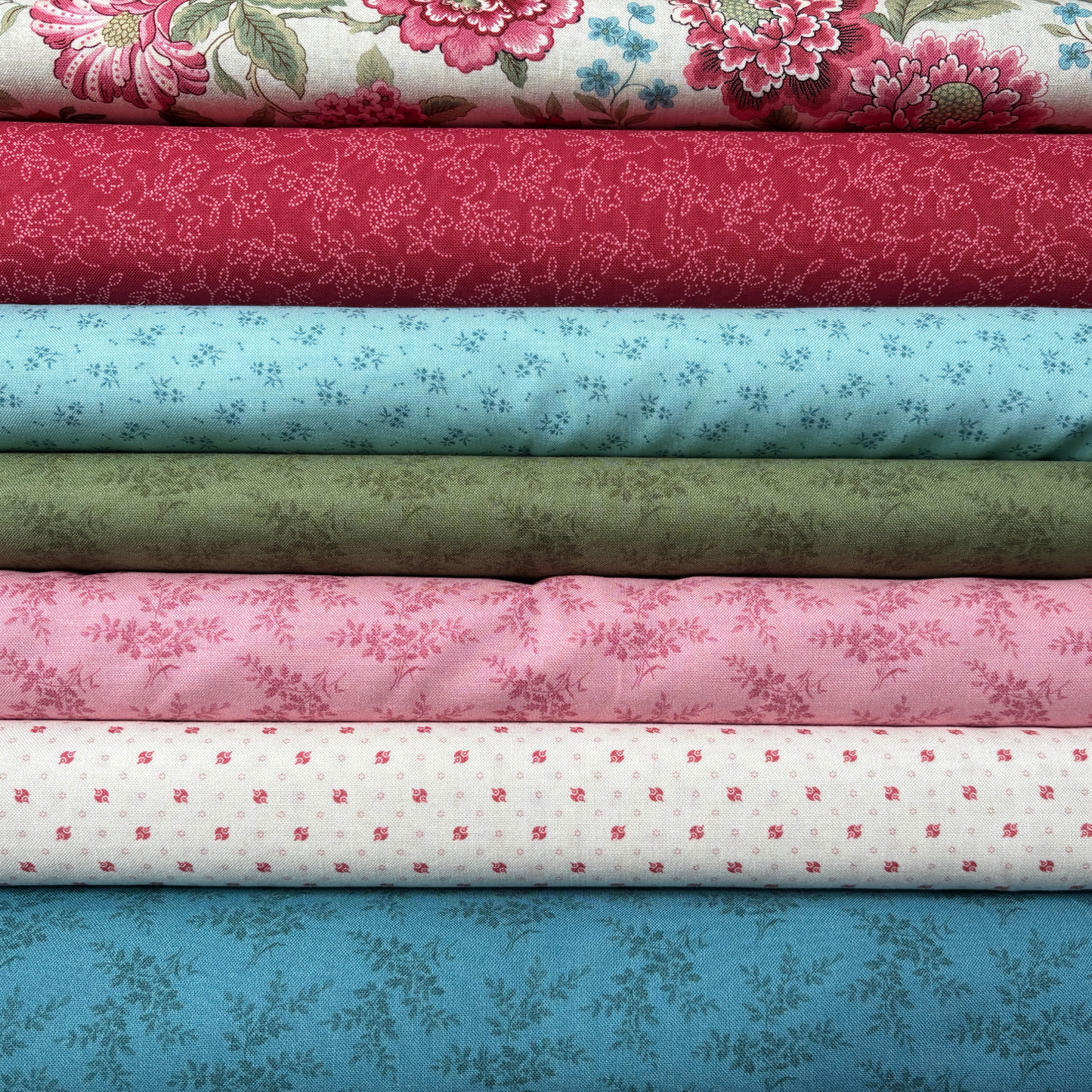 Stack of colorful floral and patterned fabric bolts
