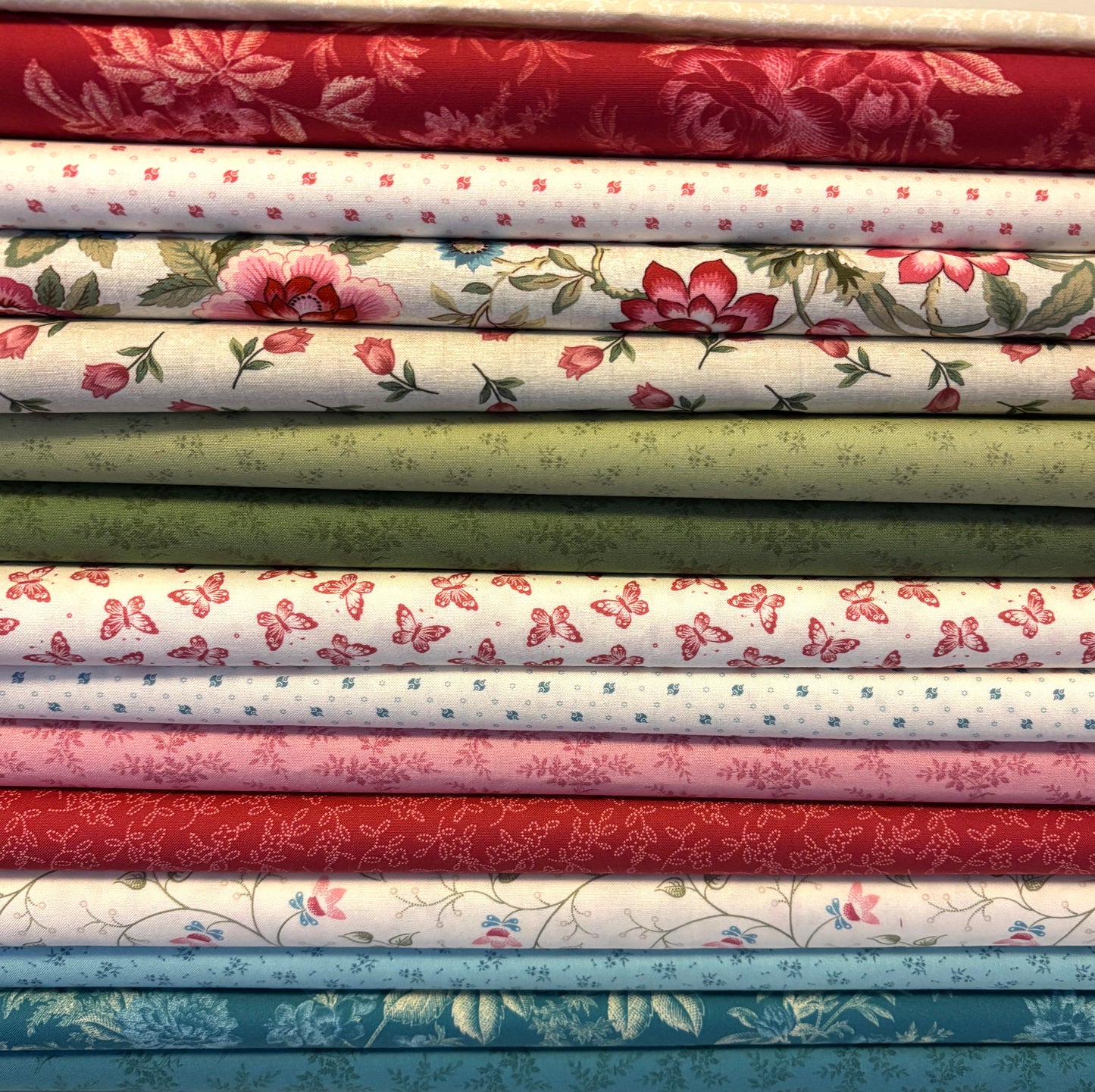 Stack of fabric bolts with floral and butterfly patterns in various colors.