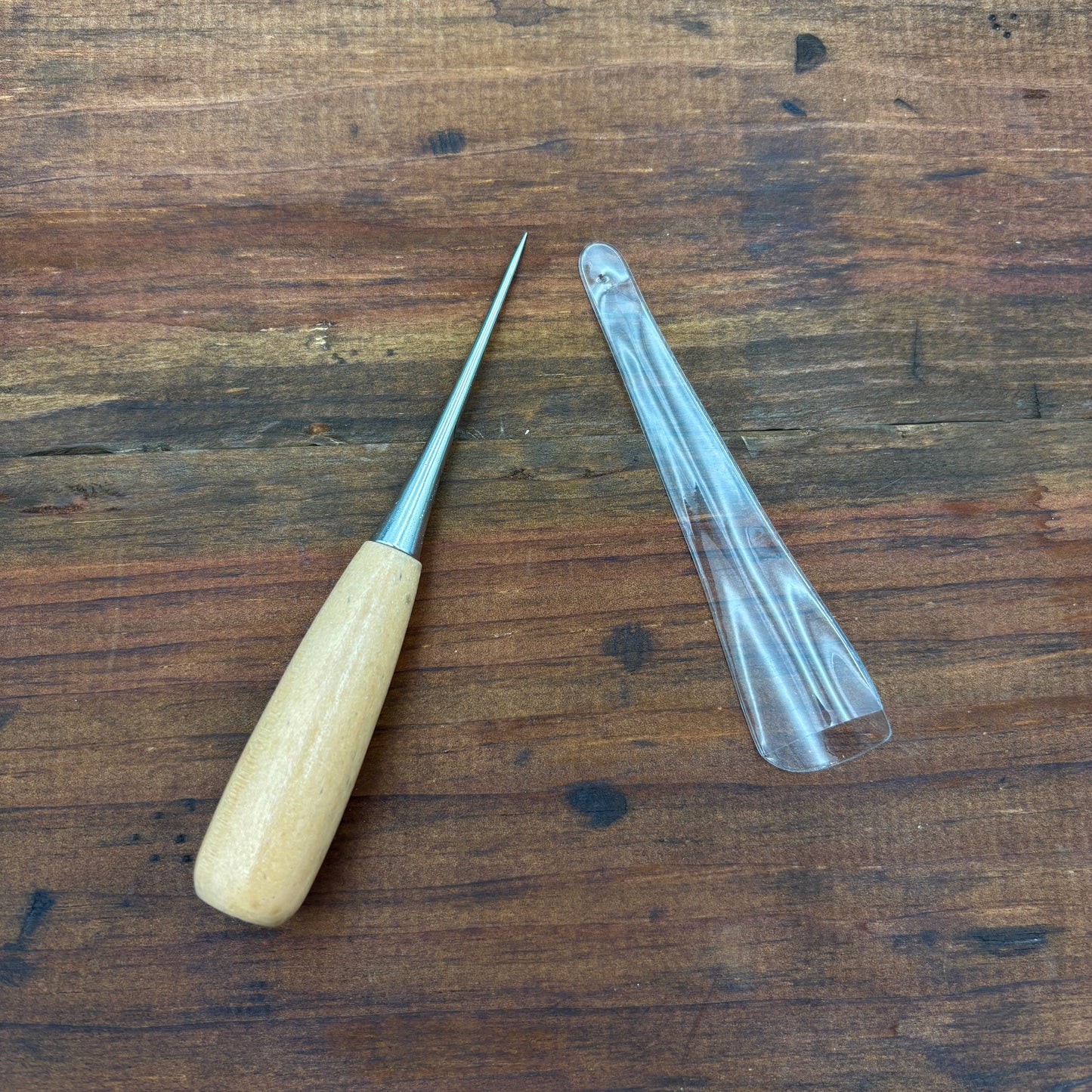Wooden-handled tool and clear plastic cover on a wooden surface