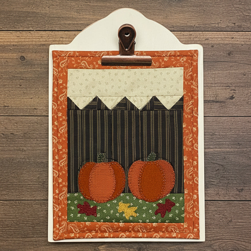 Decorative clipboard with pumpkins and leaves leaning against a white background