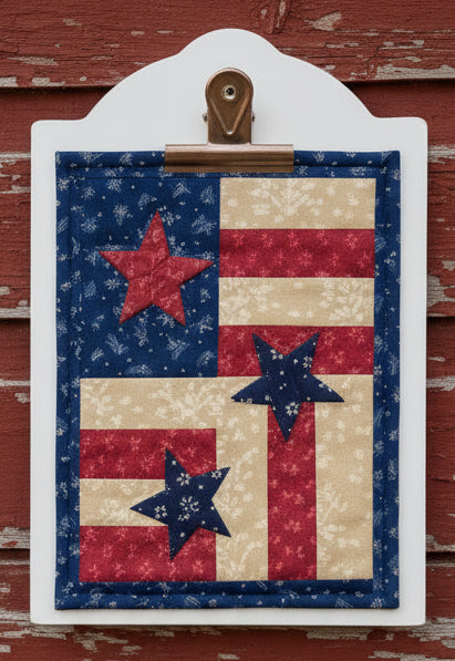 Decorative clipboard with a patriotic design featuring stars on a blue, red, on a red wood background.