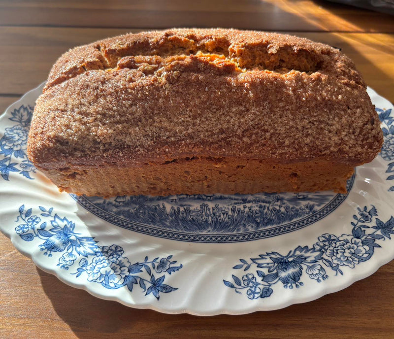 Apple Cider Doughnut Loaf sitting on a plate on a wooden table.