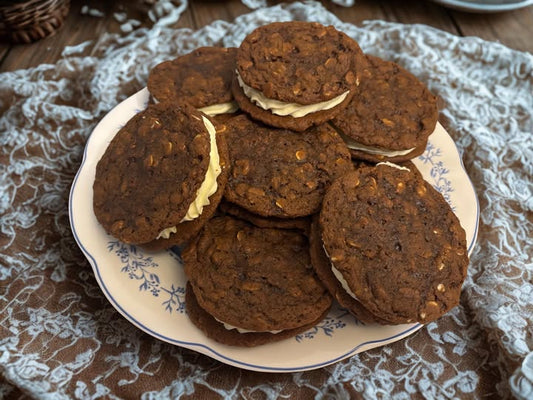 Oatmeal sandwich cookies are on a plate set on a wooden surface covered with a lace doily