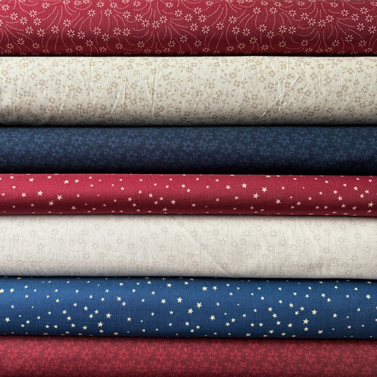 Stack of fabric swatches in red, white, blue, and beige with various patterns.