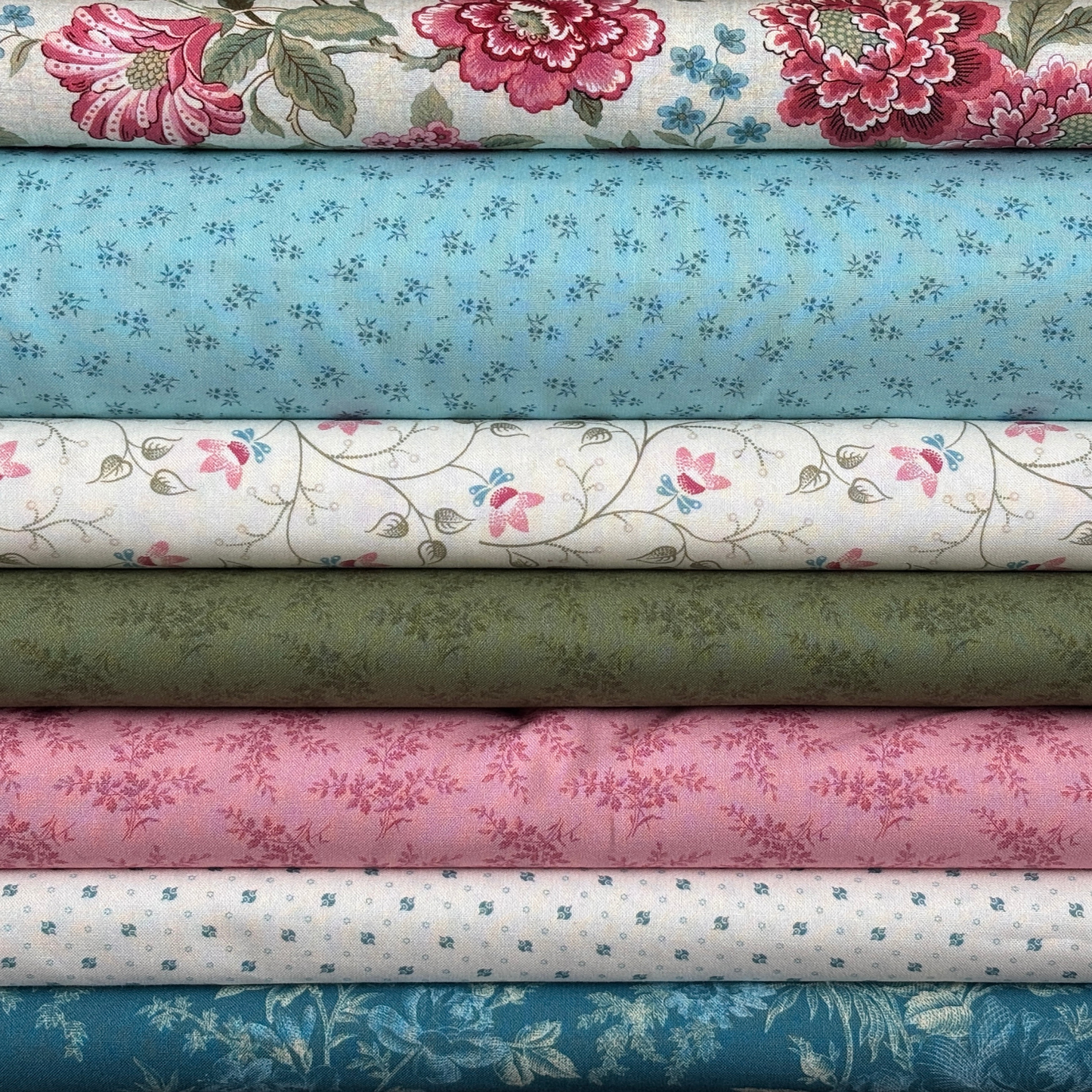 Stack of floral fabric swatches in various pink, blue, white and green colors