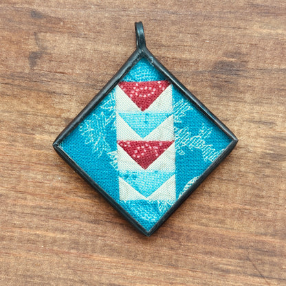 Decorative pendant with flying geese pattern on a wooden surface