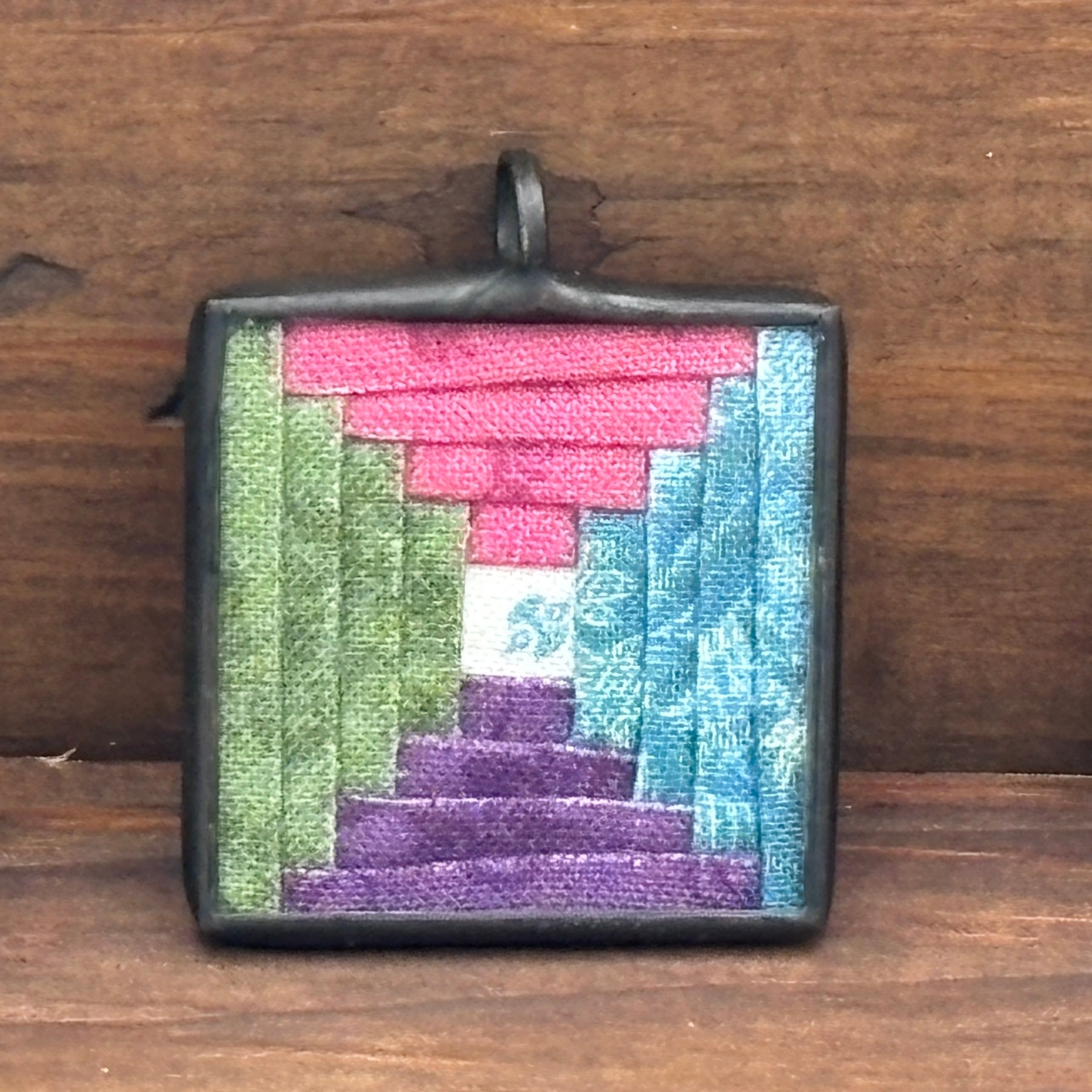 Square pendant with woven pattern on a wooden surface