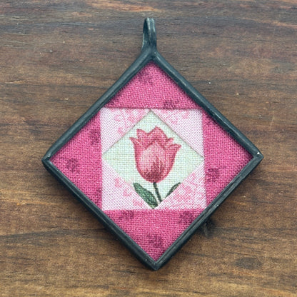 Square pendant with pink tulip design on a wooden surface