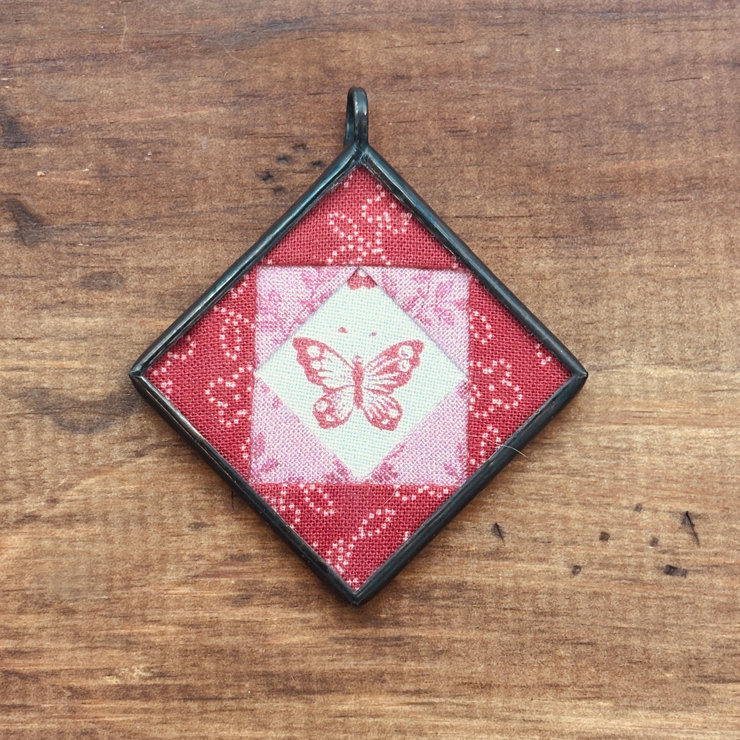 Decorative pendant with butterfly design on a wooden surface