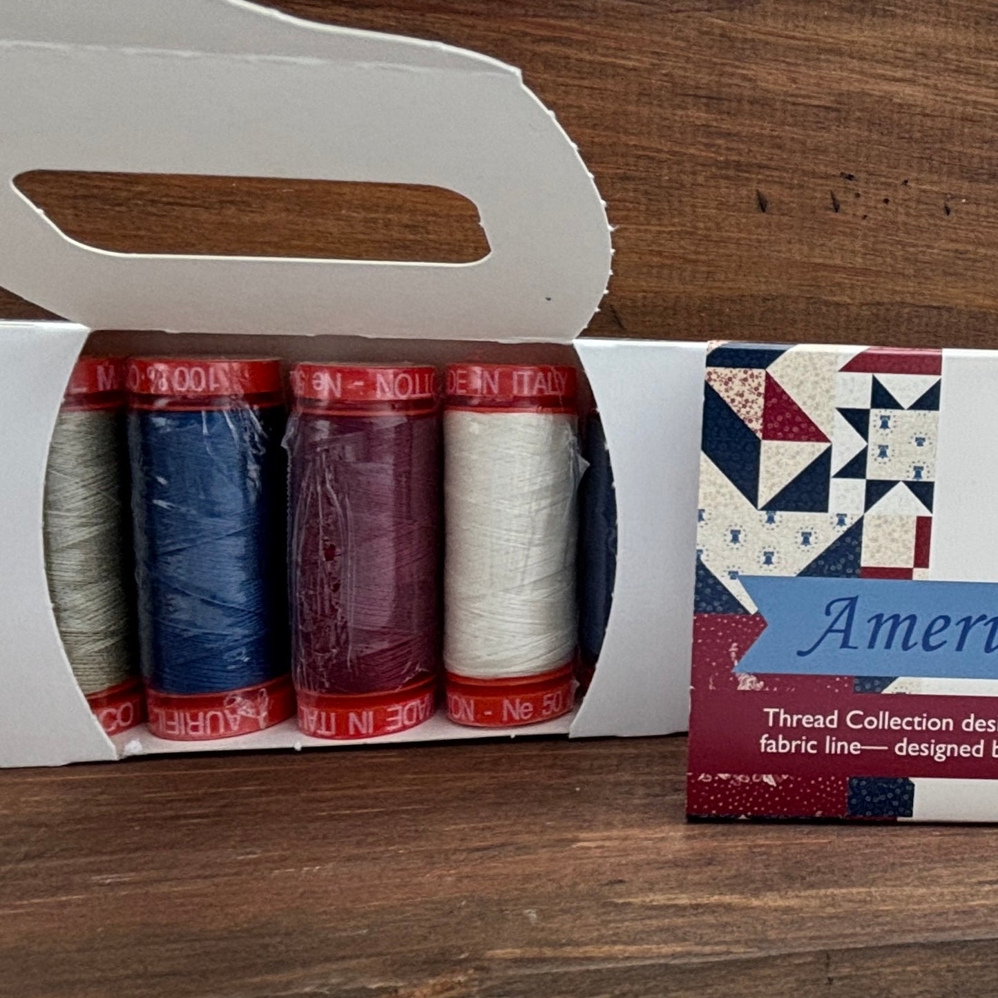 Thread collection in a box with a visible brand label on a wooden surface