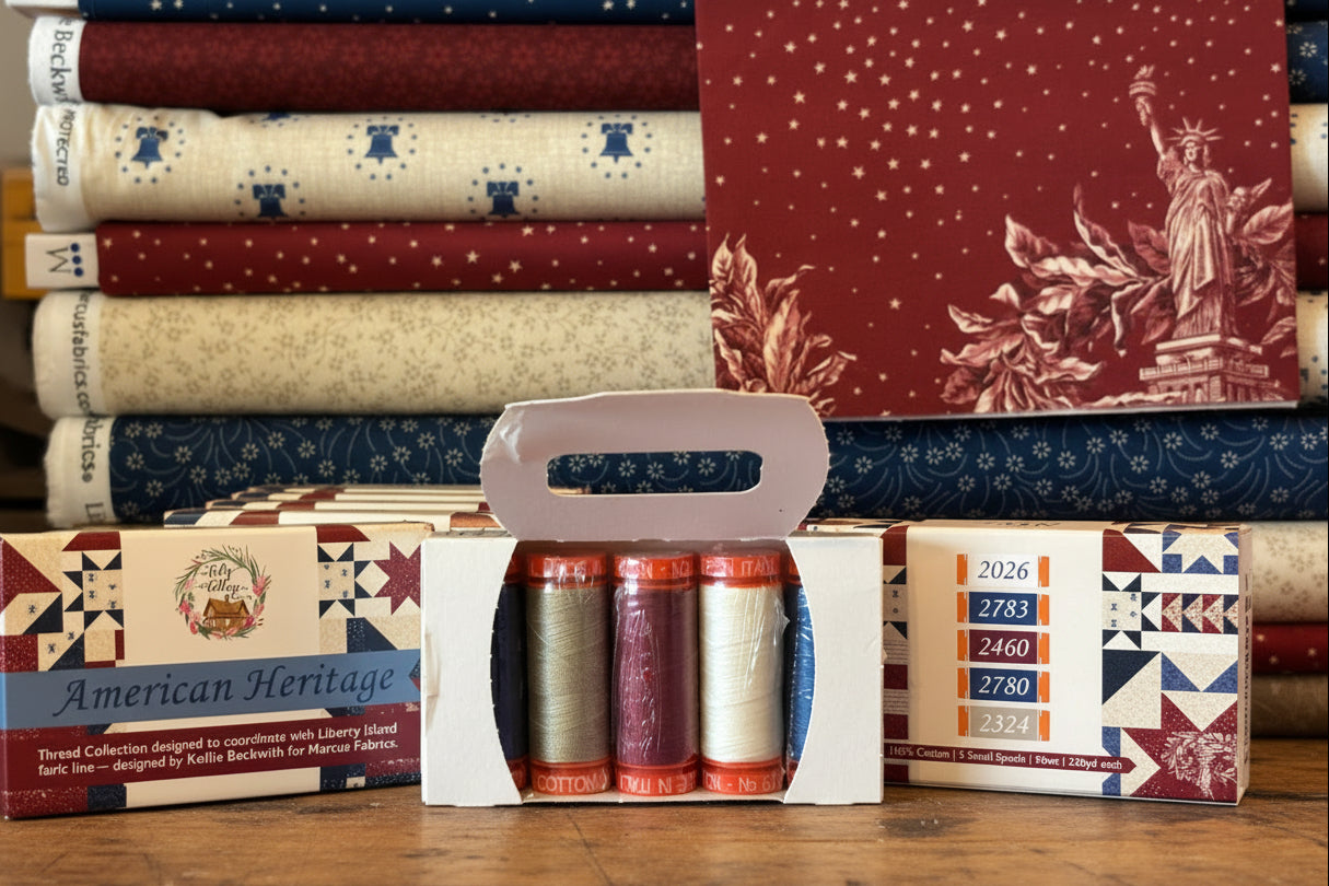 Collection of fabric bolts and thread spools on a cutting mat with 'American Heritage' branding.
