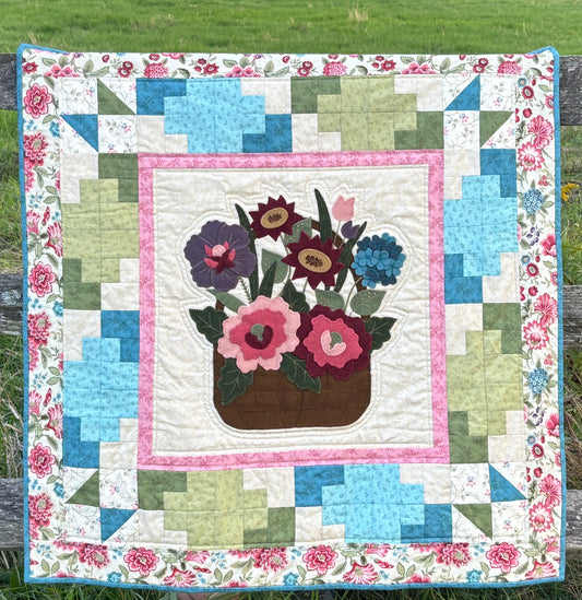 Quilt with floral design and flower pot hanging on a wooden fence