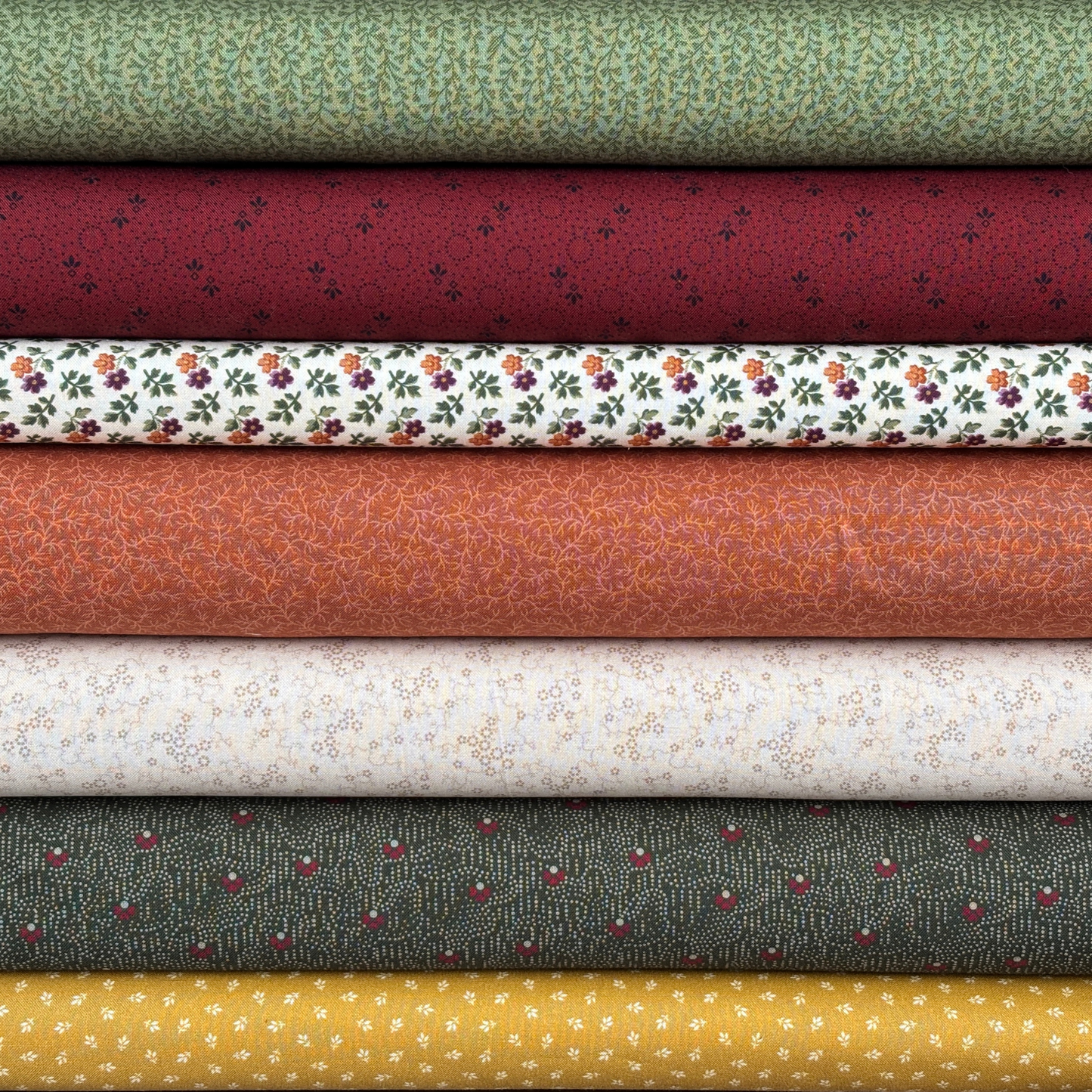 Stack of various patterned fabric bolts in different colors.
