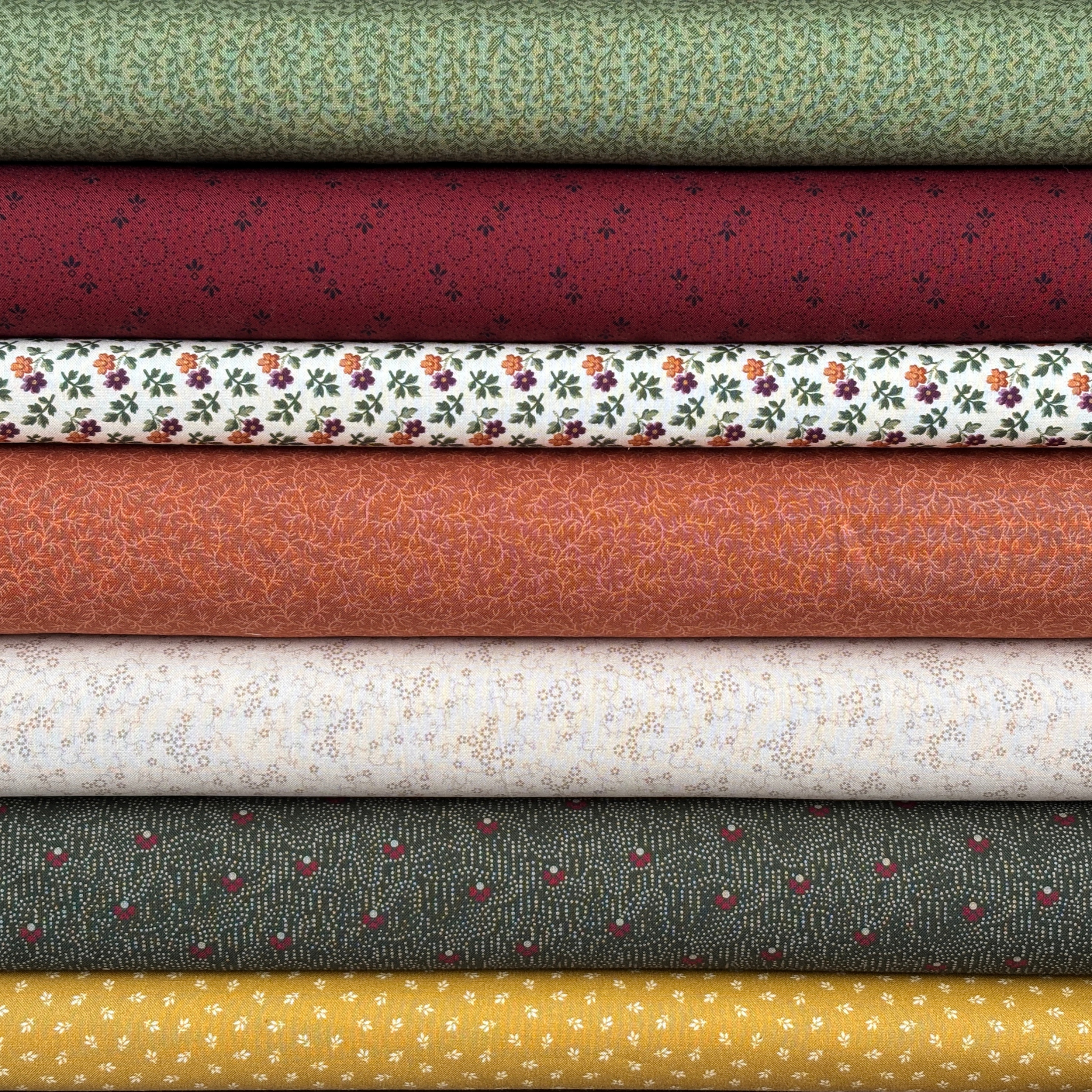 Stack of various patterned fabric bolts in different colors.