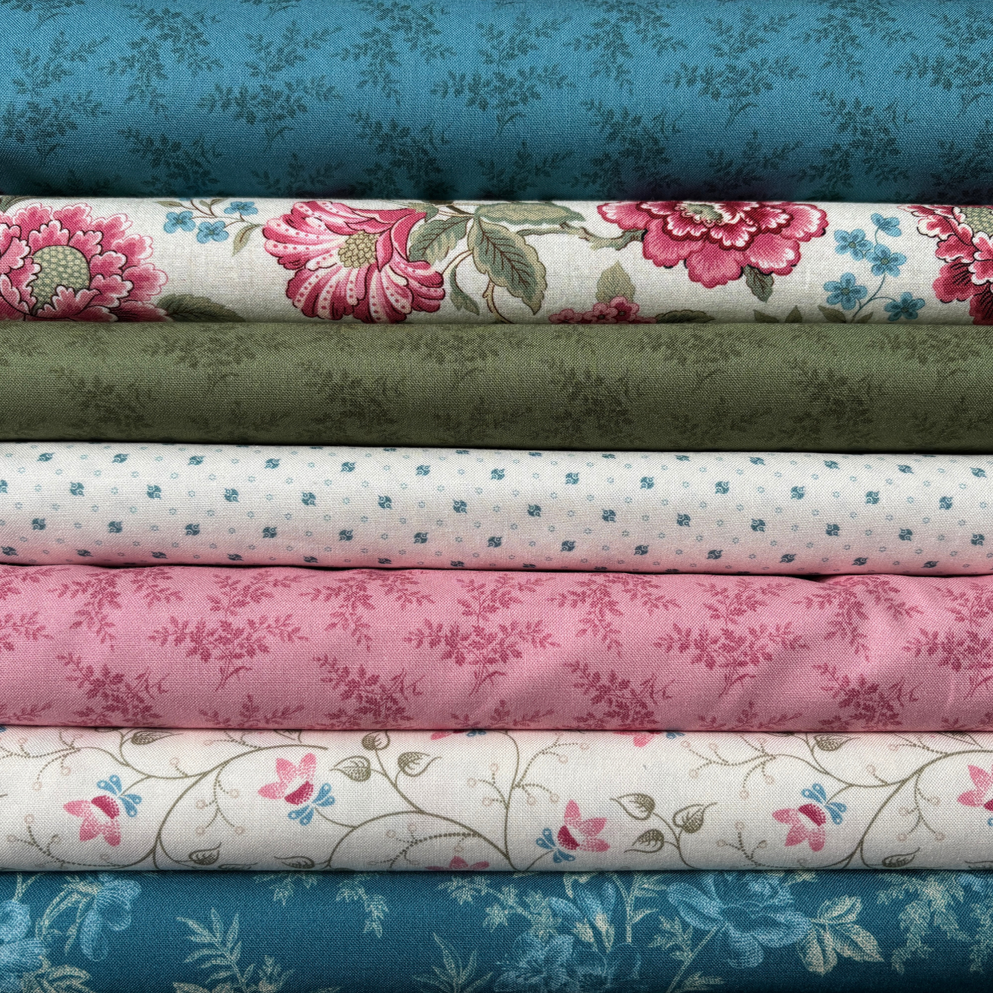 Stack of floral and patterned fabric rolls in various colors.