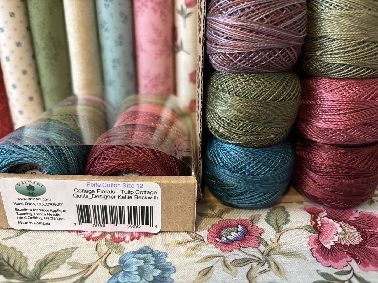 Perle Cotton balls in various colors on a floral fabric background