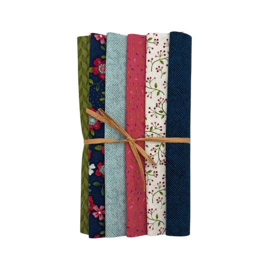 A bundle of six folded fabric pieces tied together with a tan string, showing different patterns and colors including navy floral, sage green floral, light blue, pink floral, and dark navy solid.