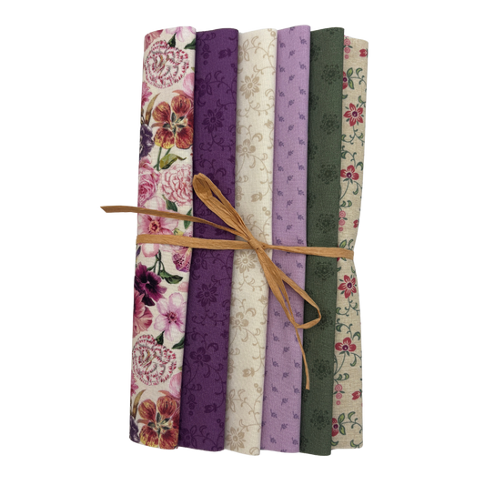 A bundle of six folded fabric pieces tied with a tan string, showing floral and patterned designs in pink, purple, cream, and olive green on a white background.