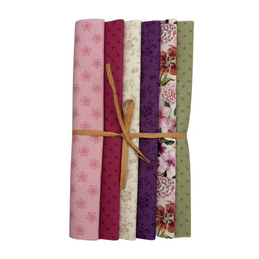A bundle of six folded fabric swatches tied with a tan string, showing assorted floral and patterned designs in pink, burgundy, cream, purple, red, and sage green on a white background.