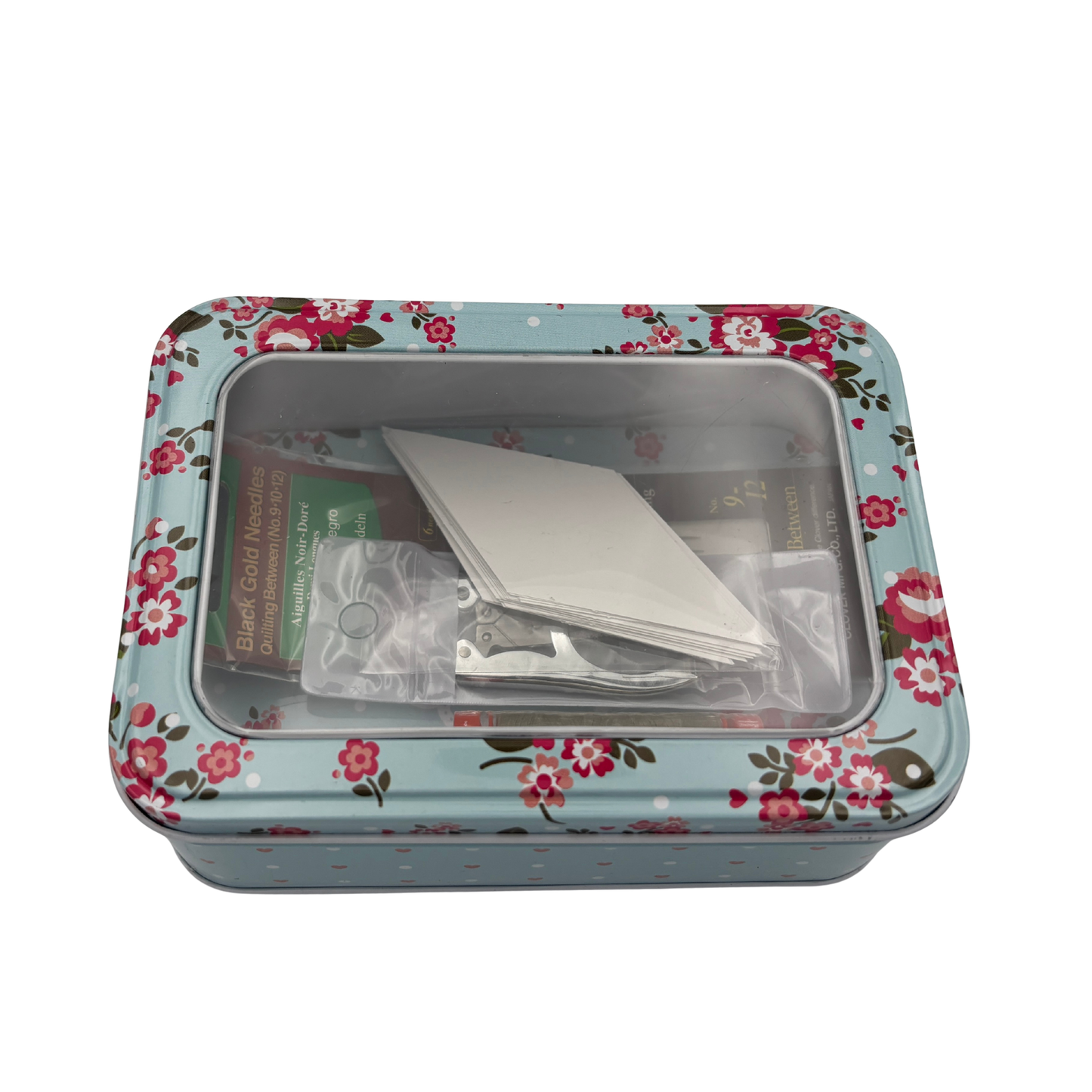Floral-patterned tin box with items inside on a white background