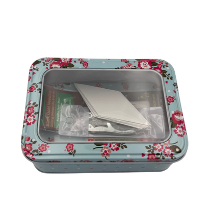 Floral-patterned tin box with items inside on a white background