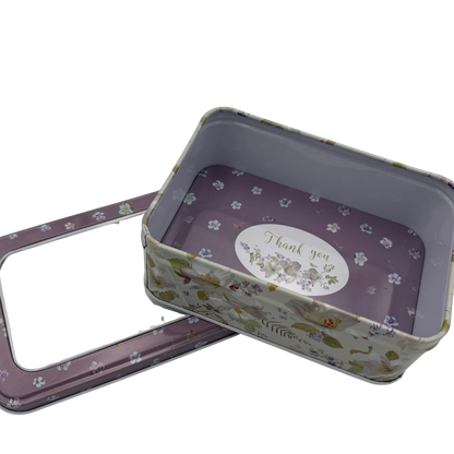 Floral-patterned metal tin with lid on a white background