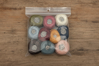 Assorted spools of thread in a clear plastic bag on a wooden background
