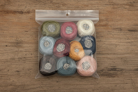 Assorted spools of thread in a clear plastic bag on a wooden background