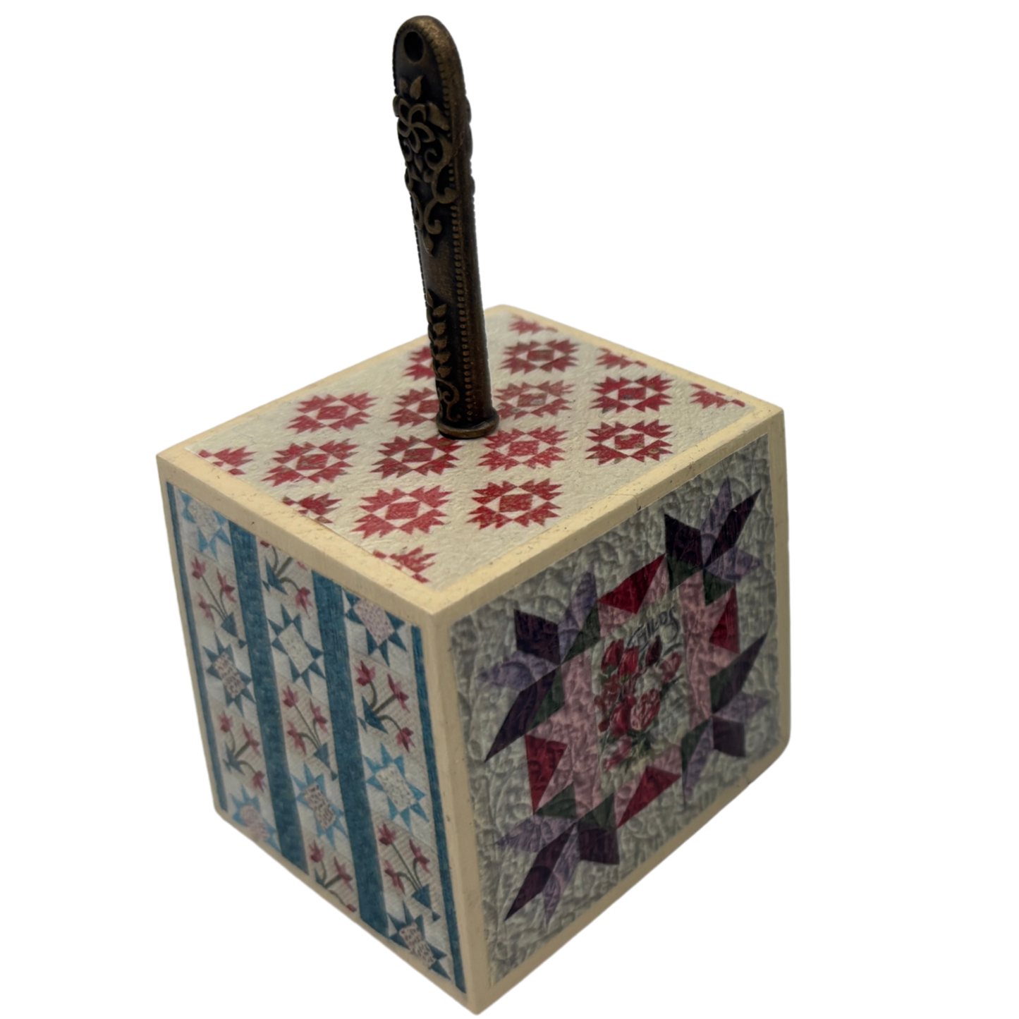 Wooden block with quilt patterns and a seam ripper on a white background