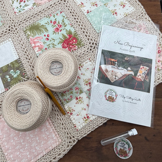 Quilting materials including fabric, yarn, and a pattern book on a wooden surface.