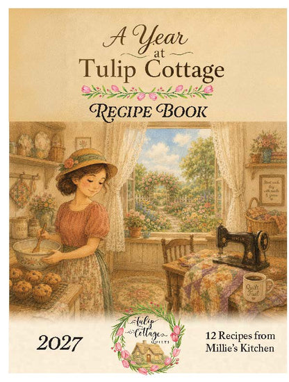 Front cover of the book 'A Year at Tulip Cottage Recipe Book' showing a vintage-style illustration of a woman mixing ingredients in a cozy kitchen, with a window view of a garden, sewing machine, flowers, and the text '2027' and '12 Recipes from Millie's Kitchen'.